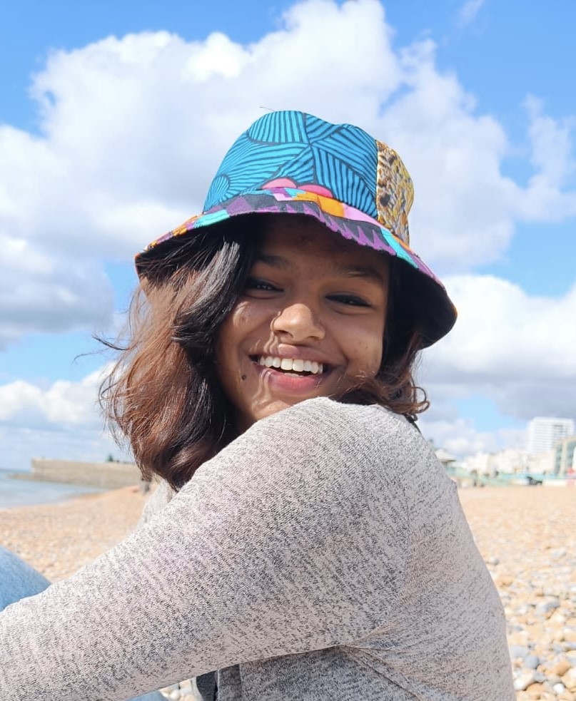 Sabeena sat on a beach in the sunshine grinning at the camera